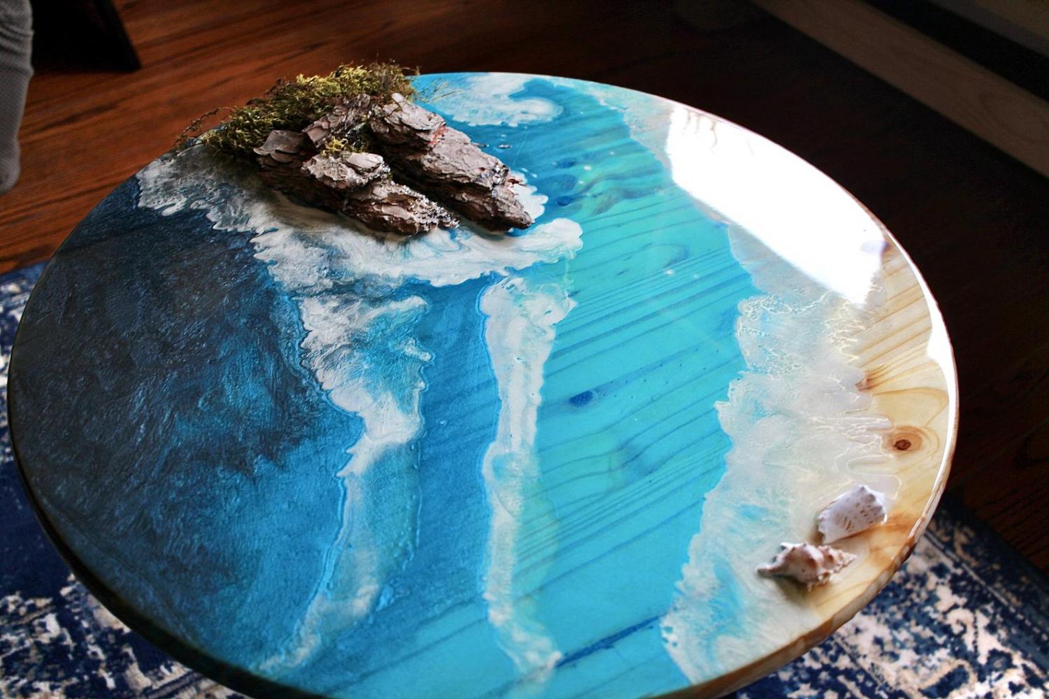 A circular epoxy table made to look like the shore of an ocean A circular epoxy table made to look like the shore of an ocean