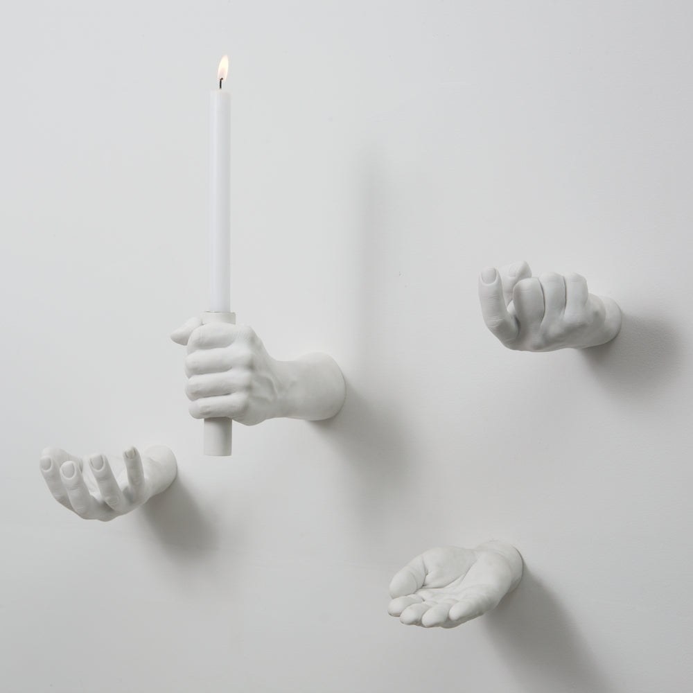 White Areaware Hand Hooks mounted on a wall holding a candle and small objects