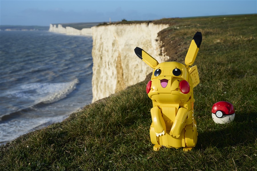 Brick-built Pikachu figure beside a Pokeball in an outdoor scene