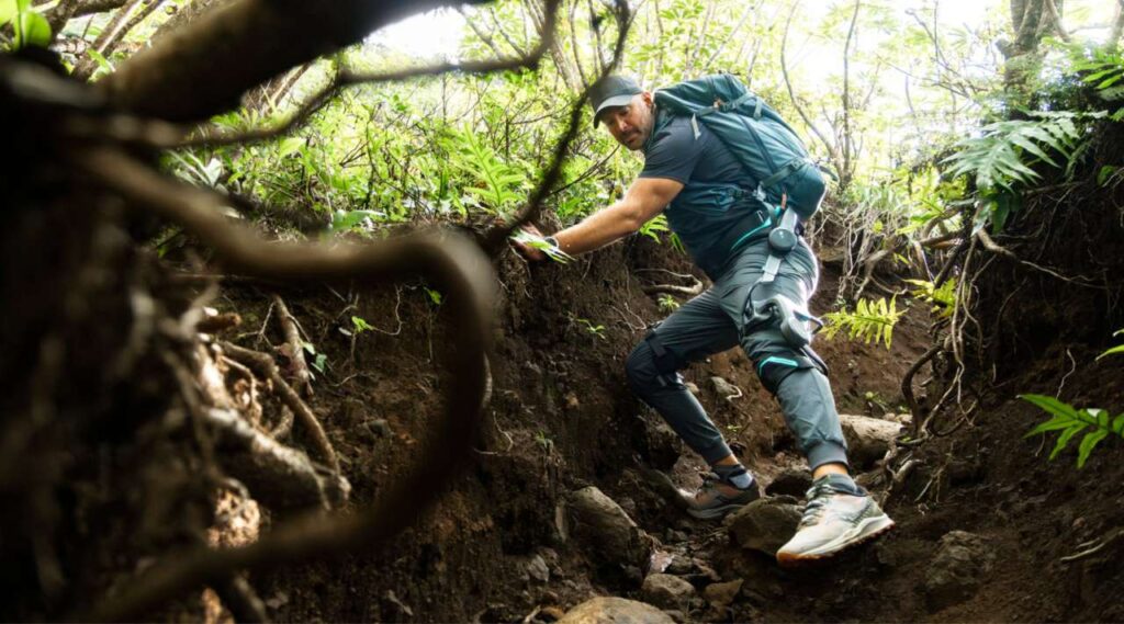 Hiker wearing Vastnaut One exoskeleton while descending a forest trail