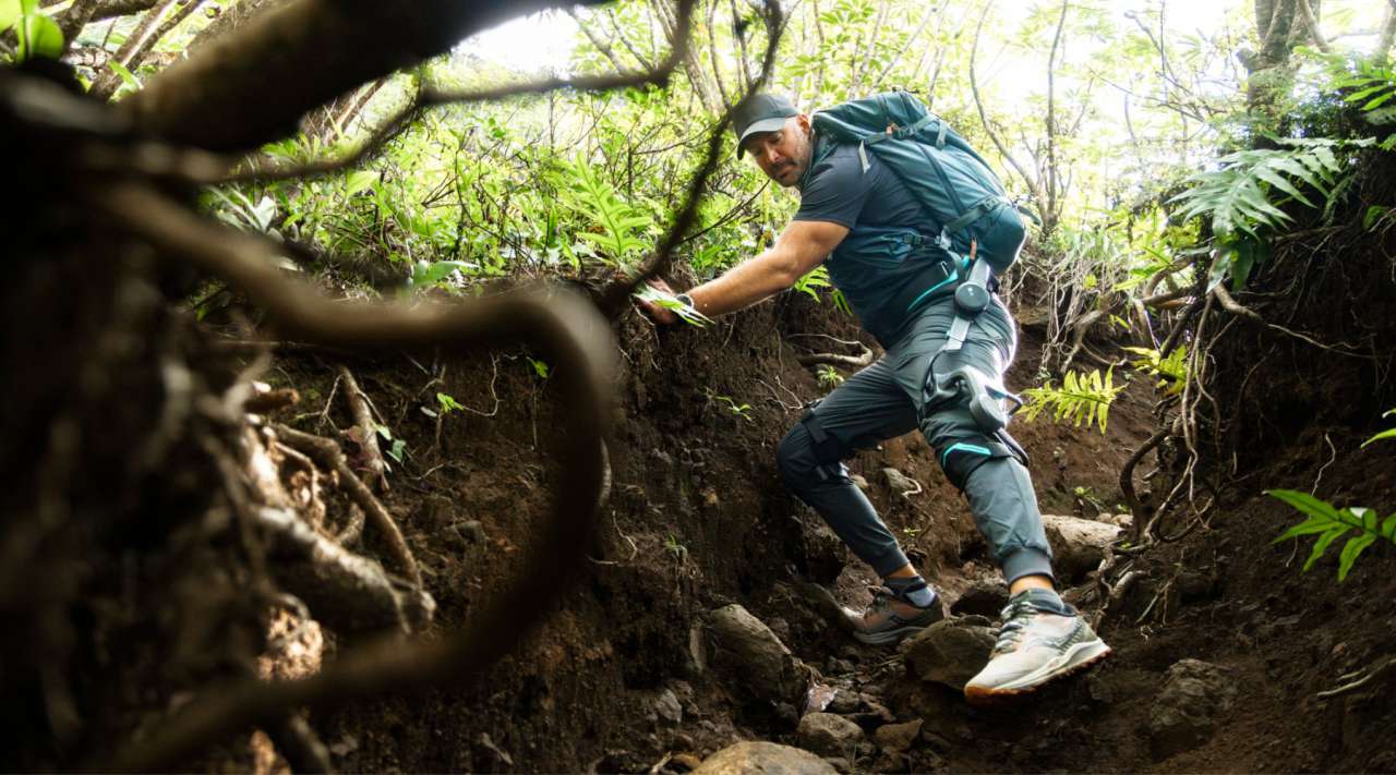 Hiker wearing Vastnaut One exoskeleton while descending a forest trail