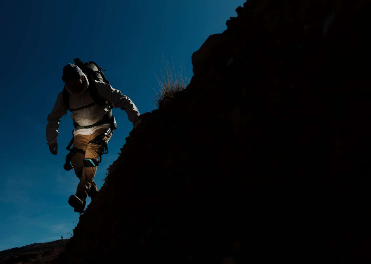 Hiker using Vastnaut One exoskeleton while climbing a steep trail