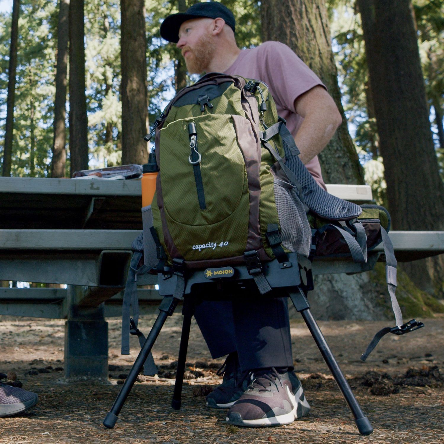 Mojoh Ryzer Go lifting a hiking backpack off the ground at a campsite