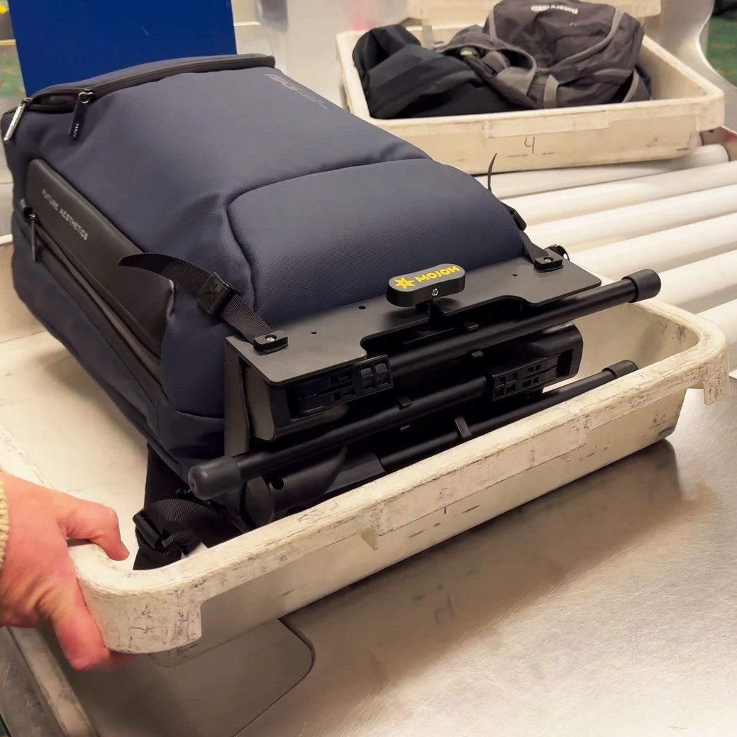 Mojoh Ryzer Go attached to a travel bag in an airport setting
