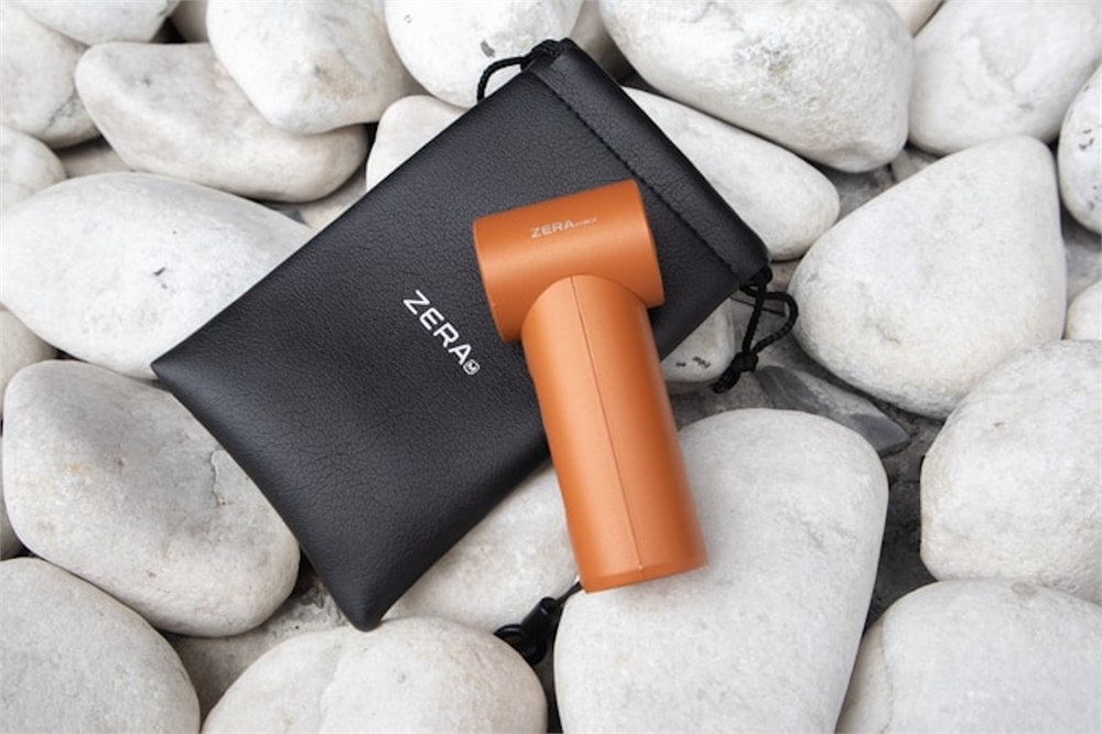 Orange ZERA mini cooling fan with a small carrying pouch