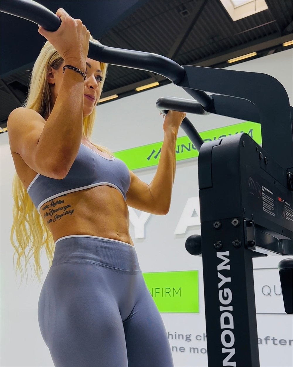 A person using the OMNI X1 assisted pull-up bar at a fitness expo