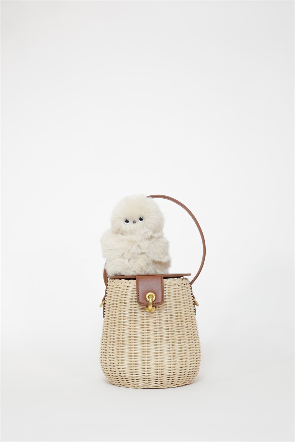 Ivory Mirumi robot sitting on a woven handbag in a studio product photo