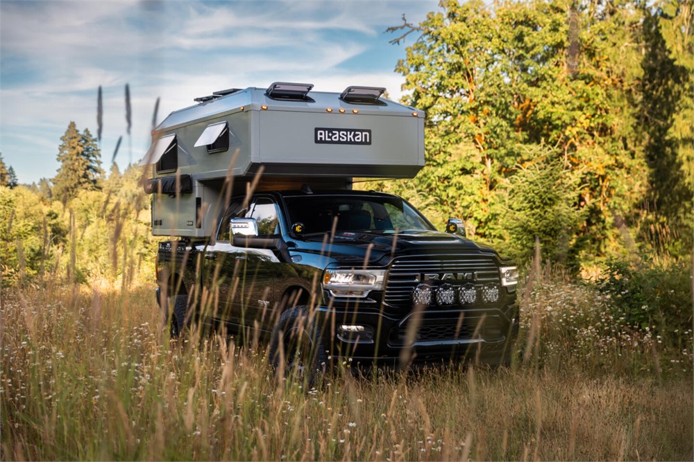 Alaskan HS 640 camper mounted on a black pickup in a field
