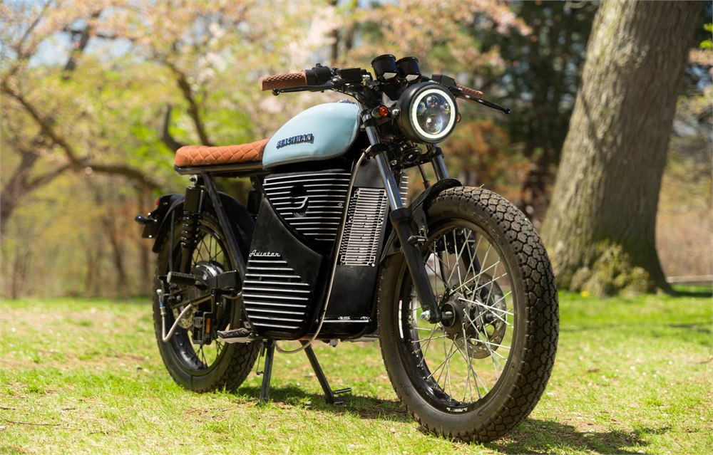Beachman Aviator electric cafe racer parked outdoors with pale blue tank and brown seat