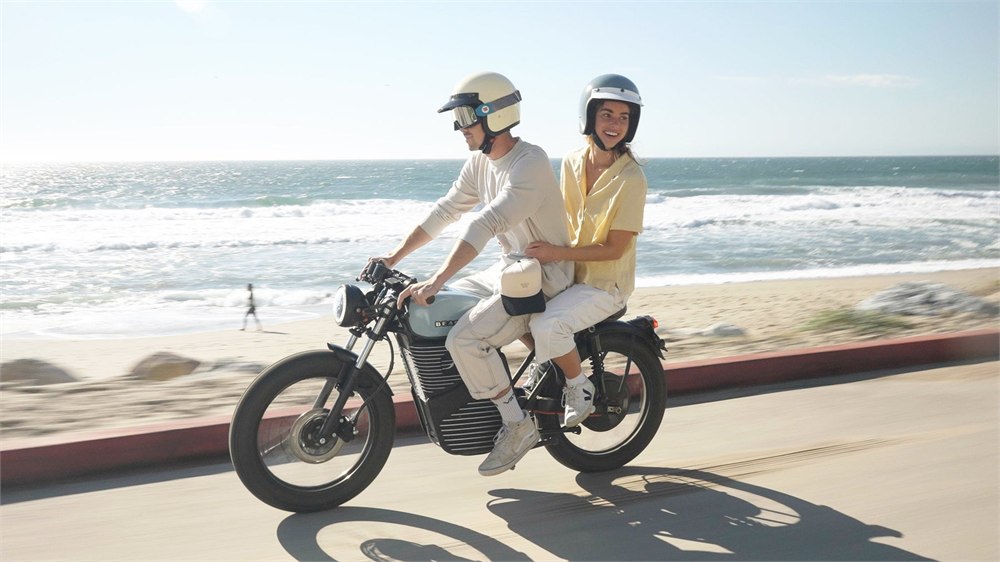 Two Beachman electric cafe racer bikes riding near the coast with passengers
