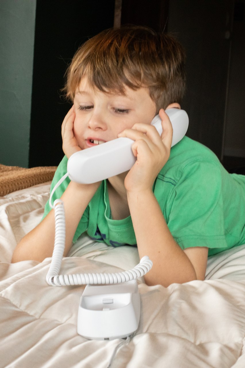 Child using the Pinwheel Home handset while lying on a bed