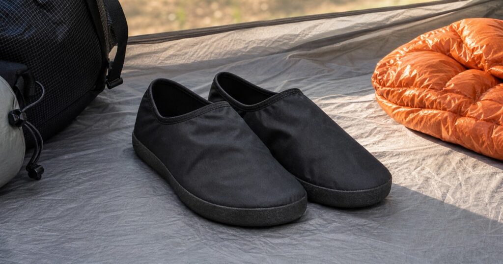Ultralight black camp shoes on a tent floor with backpacking gear