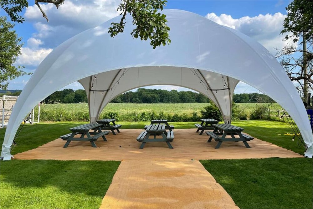 White DreamDomes Crossover L event dome with picnic tables underneath
