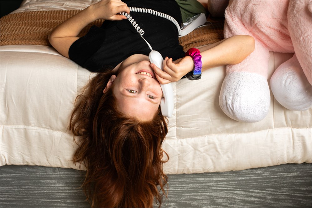 Child lounging on a bed while using the Pinwheel Home phone