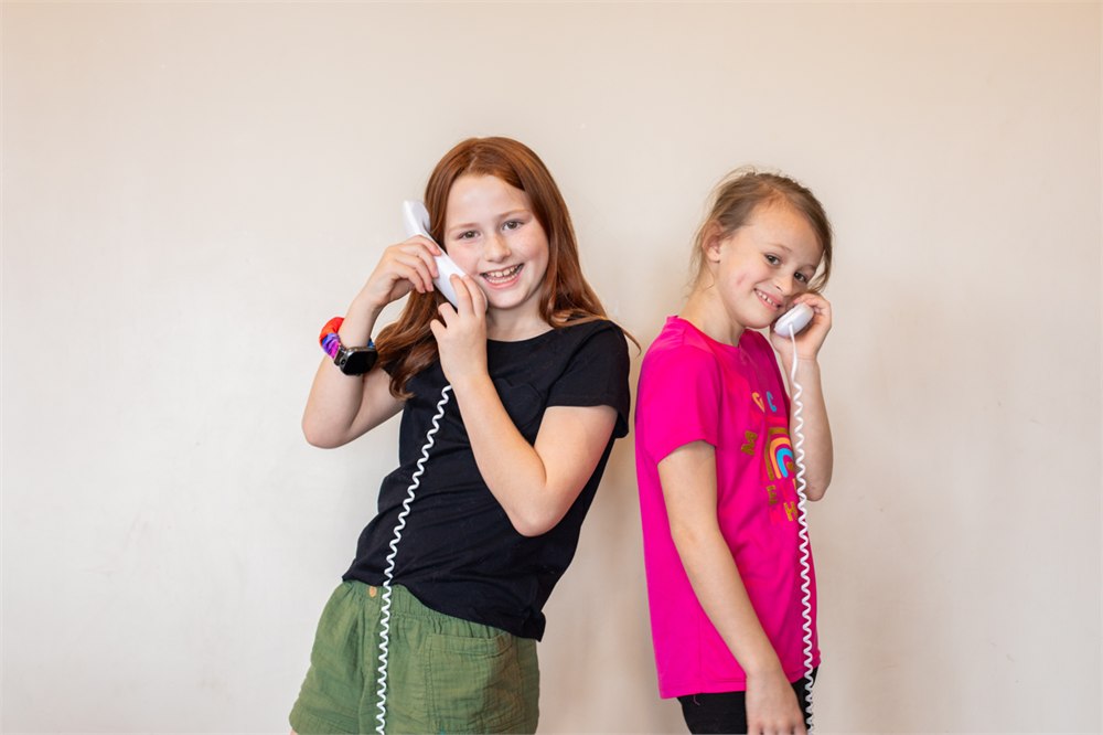 Two children using Pinwheel Home phones to talk from different rooms