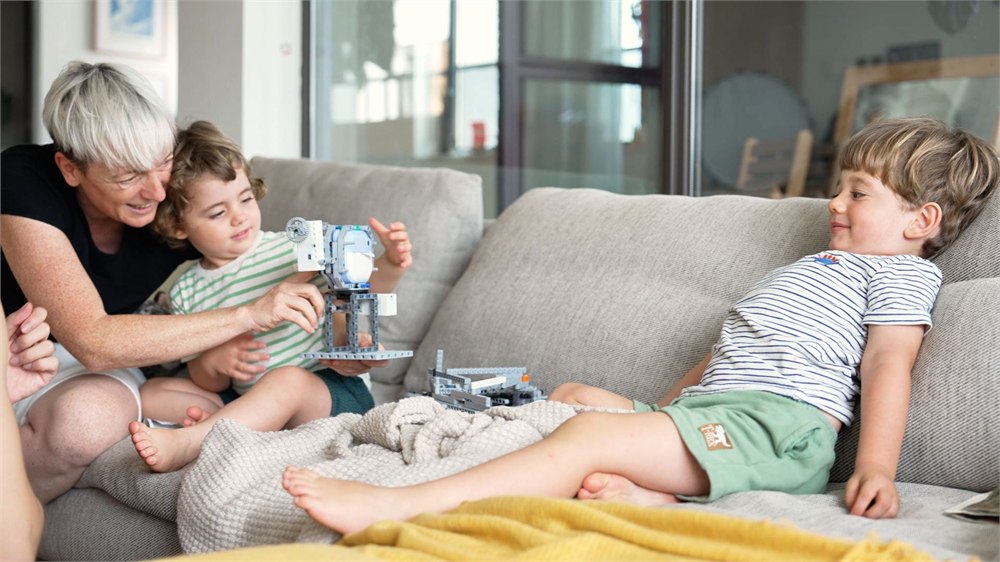 Children using CODEE screen-free coding blocks with robot builds on a couch