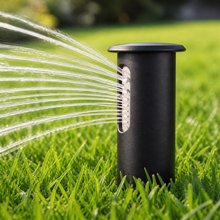 Close-up of an Irrigreen smart sprinkler head spraying water across grass.