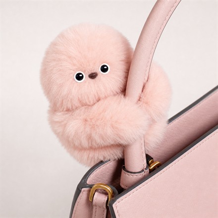 Pink Mirumi bag-charm robot hugging a handbag strap