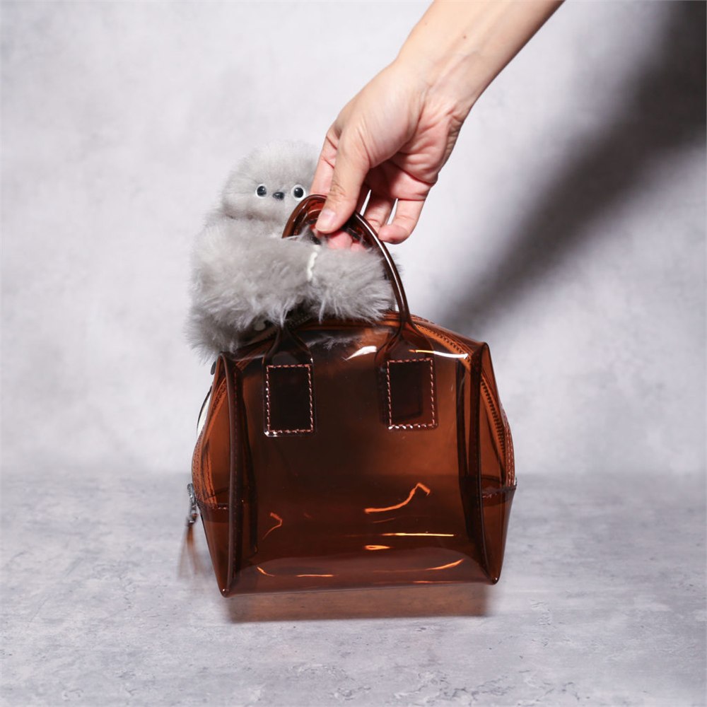 Gray Mirumi robot hugging the handles of a clear brown handbag