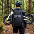 Generated product image of the Uplift backpack carrying a balance bike on a forest trail