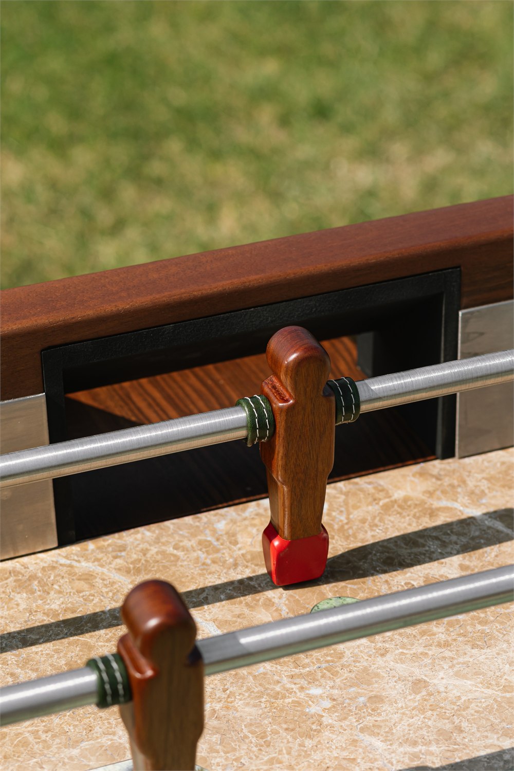 Close detail of the Orior Foosball Table player, steel rod, leather, and marble field