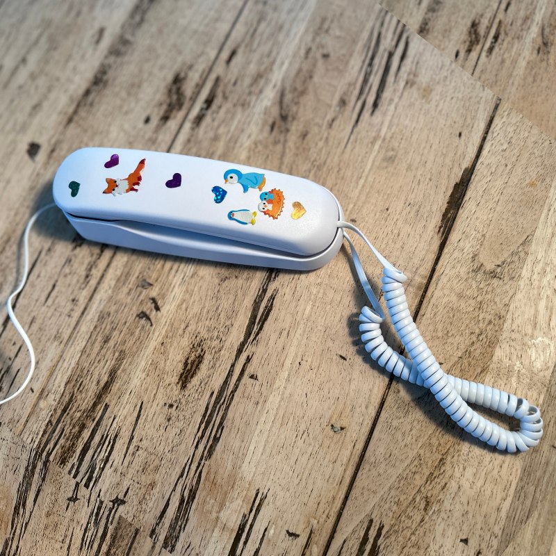 Pinwheel Home screen-free kids Wi-Fi landline phone decorated with stickers on a table