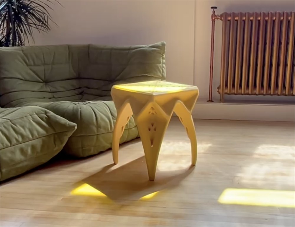QWRKhouse CAVITY yellow 3D-printed stool used as a side table beside a sofa