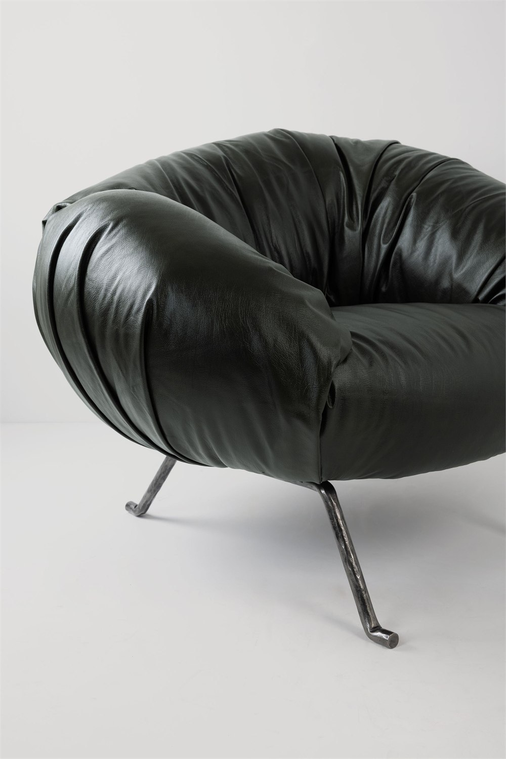 Close-up of the dark Soft Slump armchair upholstery folds and metal legs