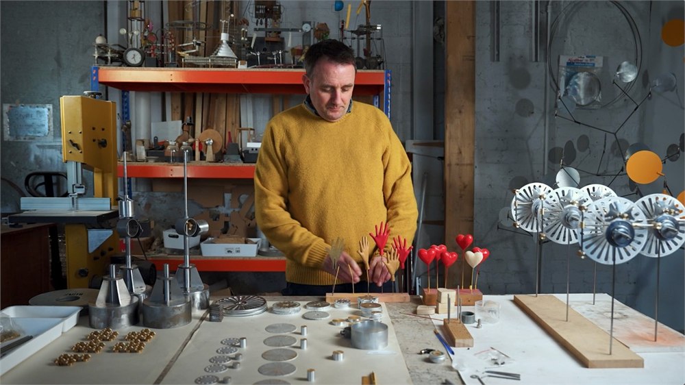 Workshop still showing Martin Smith with parts for the Solar Orbiter kinetic sculpture