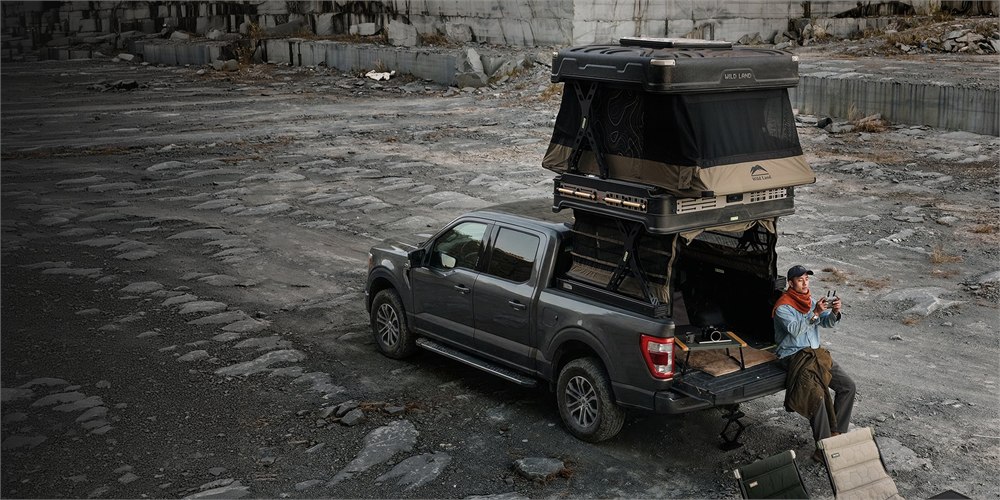 Cinch Wild Land Wingman two-story pickup camper deployed beside a rocky campsite