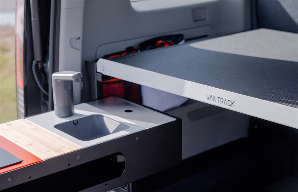 Vantrack LightCamp interior with slide-out bed and compact sink module