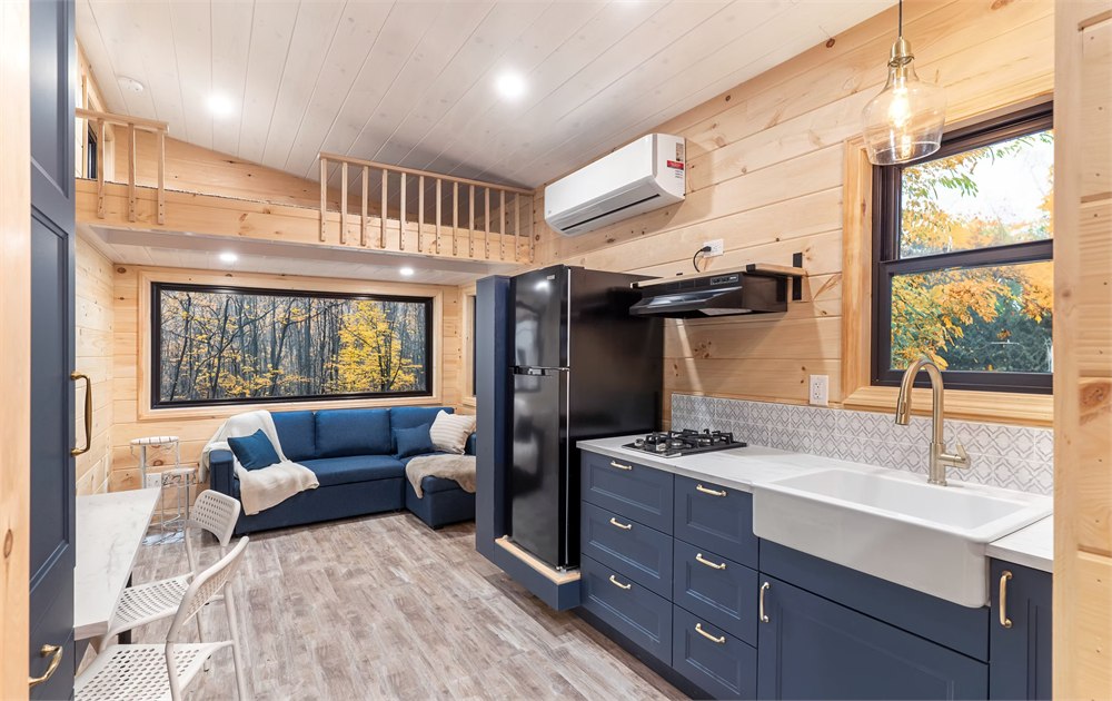 White Pine tiny house kitchen with dark cabinets, stove, sink, and wood ceiling