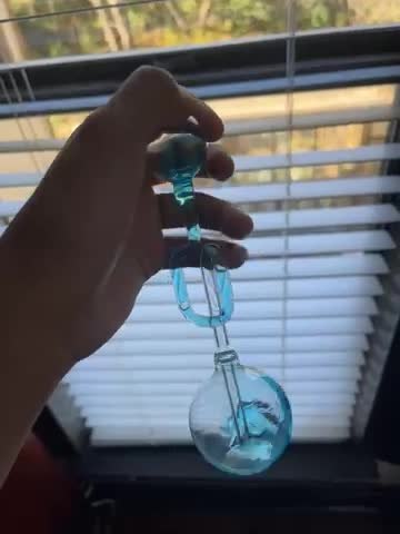 Glass hand boiler being warmed in a hand near a window