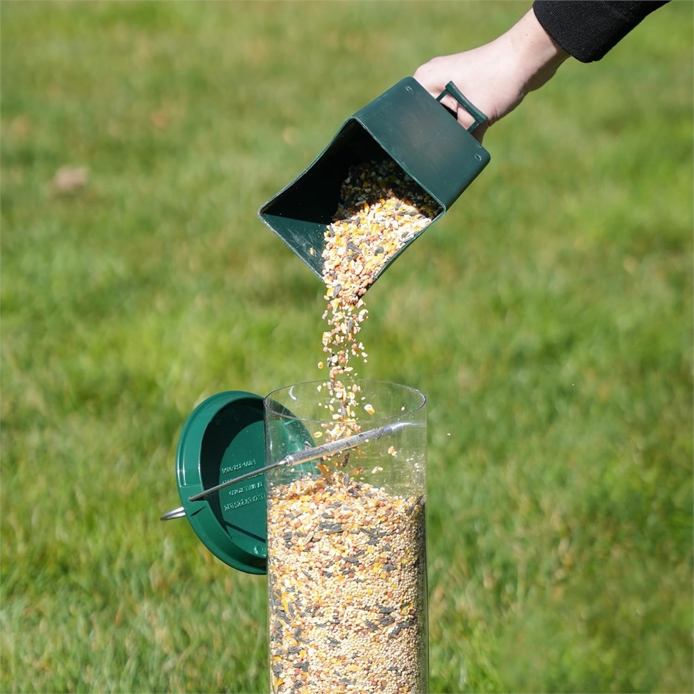 Bird seed being poured into the top of the feeder