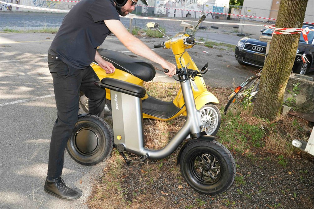 Augment 360 near a larger parked scooter for size comparison