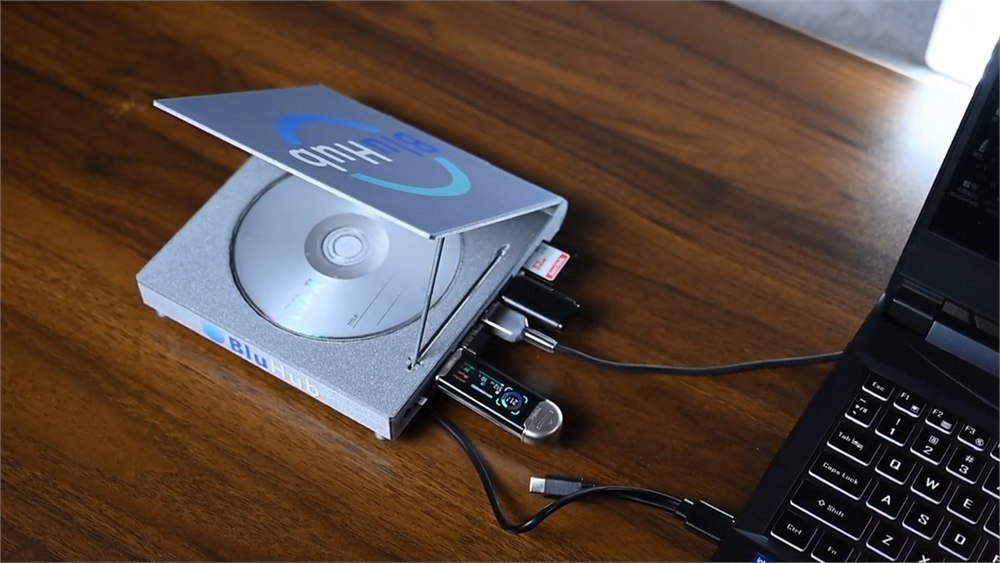 BluHub open on a desk with USB devices connected beside a laptop