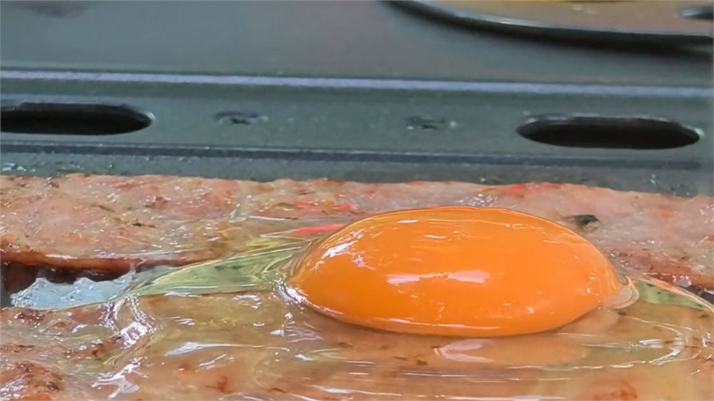 The FYREL Fold & Go griddle surface cooking breakfast-style food outdoors.