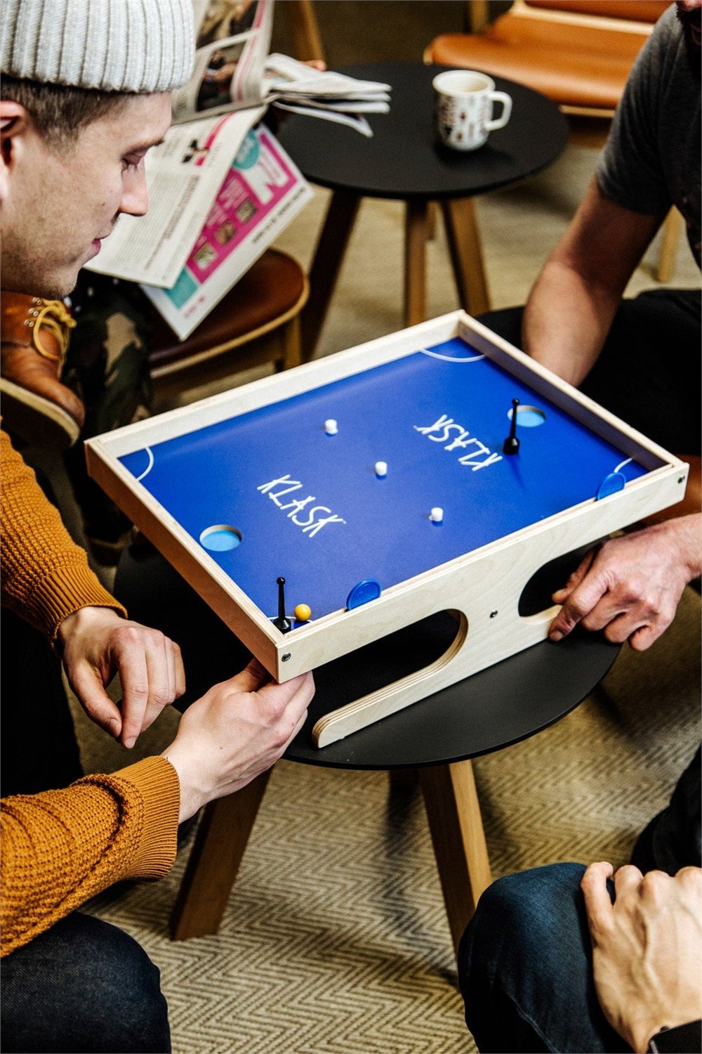 KLASK magnetic tabletop game set up with its blue playfield and wood frame