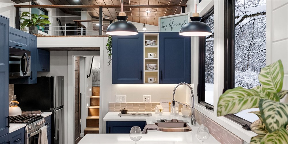 The Retirement Retreat kitchen with blue cabinets, tall windows, and loft view