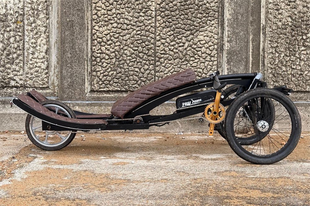 Sweren Swerv prone trike parked in profile against a stone wall