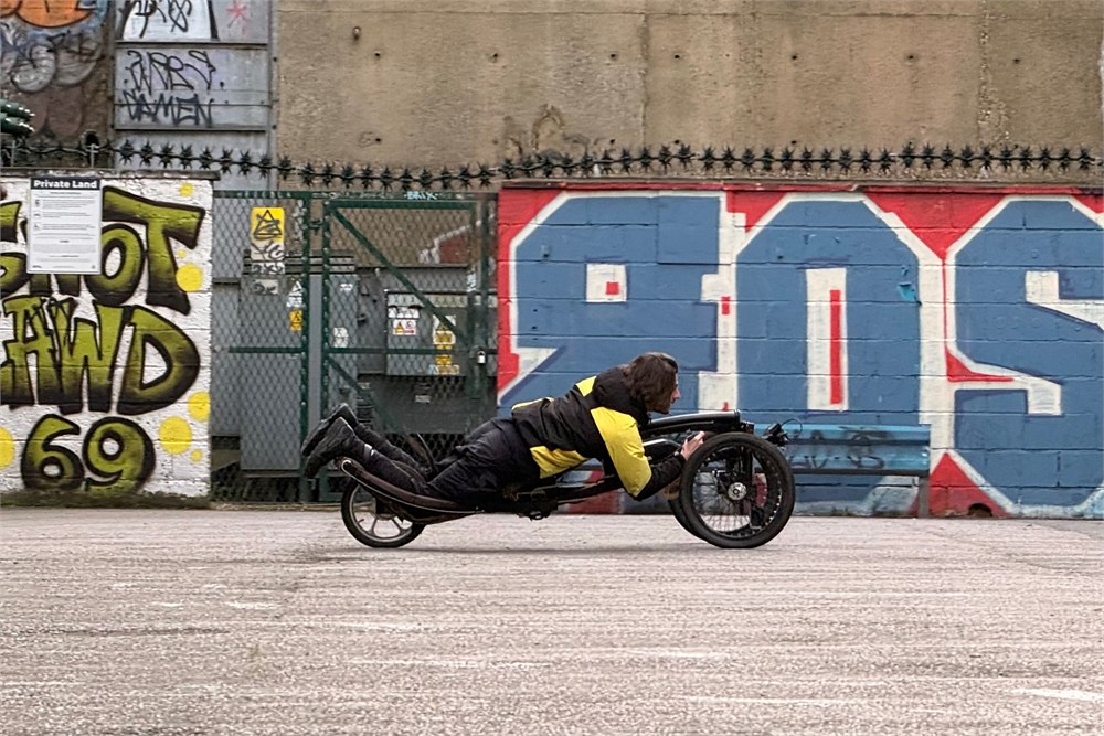 Sweren Swerv prone electric trike ridden low to the ground near an urban wall