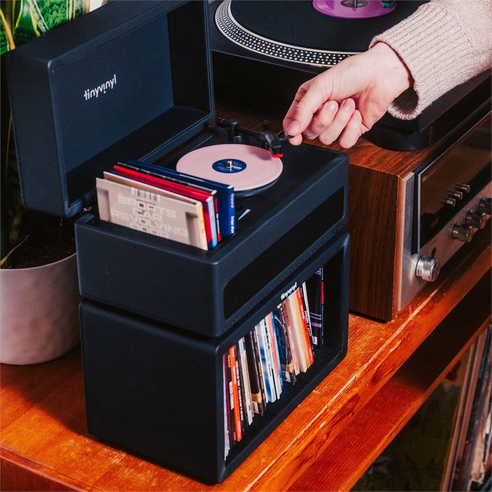 Tiny Vinyl Player playing a pink 4-inch record beside a stack of Tiny Vinyl sleeves