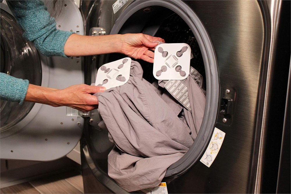 Wad-Free Bed Sheet Detangler clipped to gray sheets at a washer opening