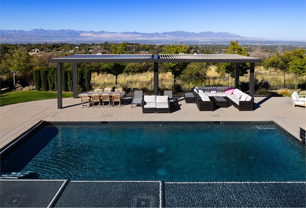 Wide poolside outdoor living area with a StruXure louvered pergola