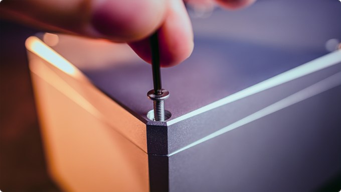 Hex key turning a corner screw in the aluminum box lid