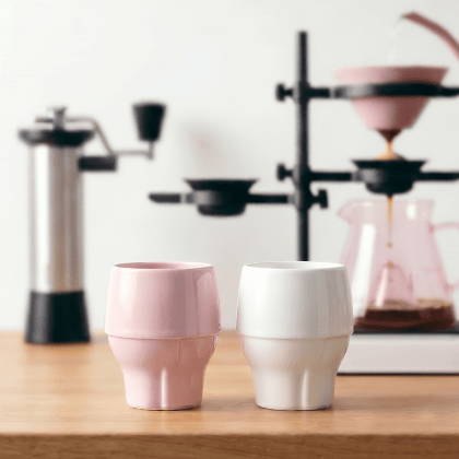 Pink and white porcelain cups beside a coffee brewing setup