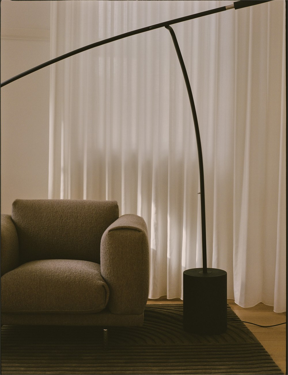 Curved mast and counterweight of the Contra lamp beside a lounge chair