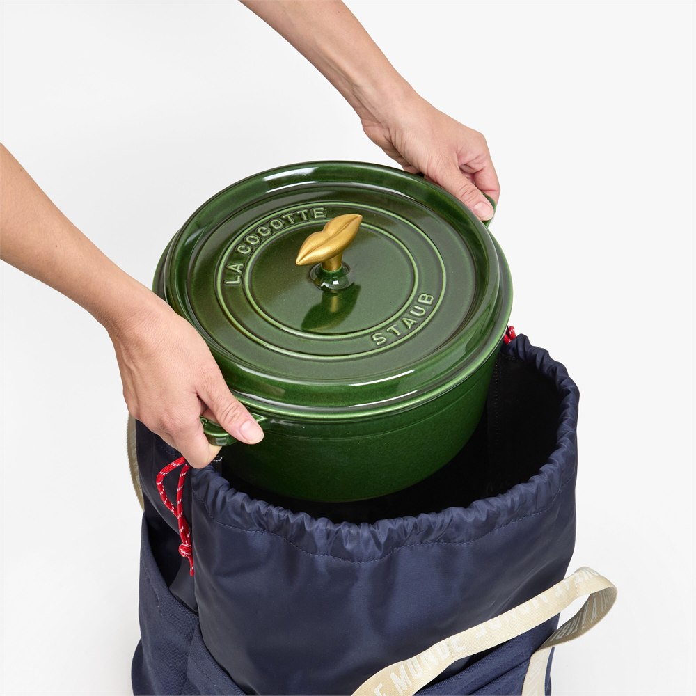 Green Dutch oven being placed into the insulated tote