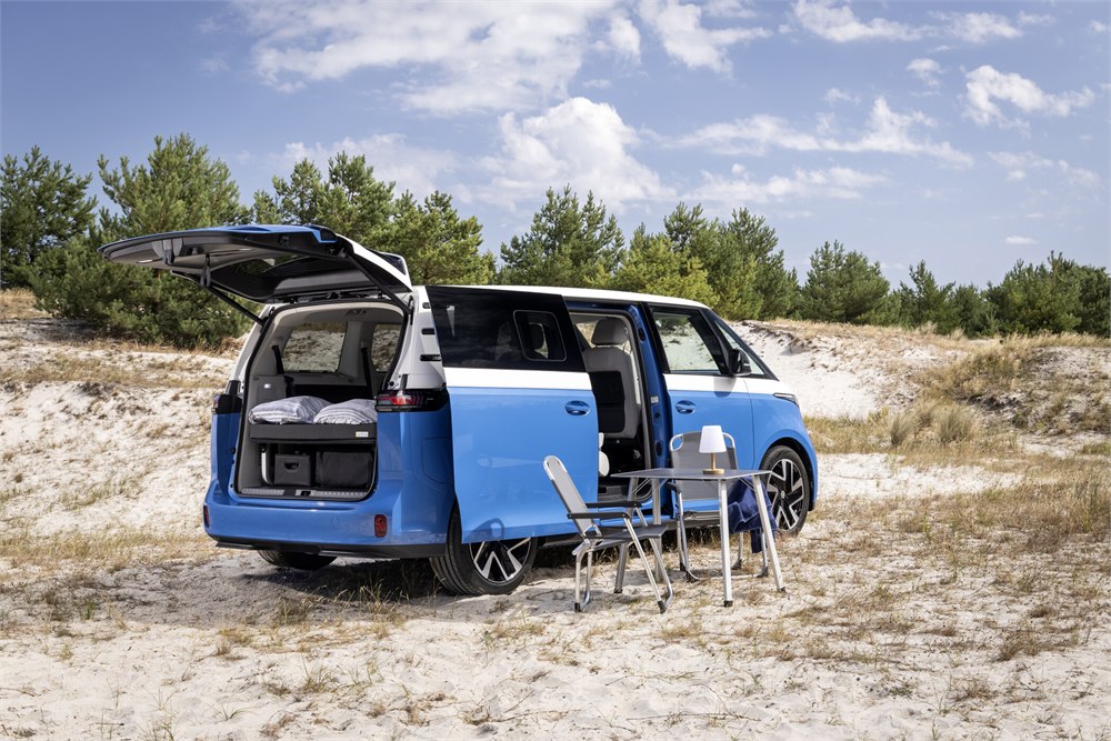 Blue and white electric camper van with bed and outdoor seating