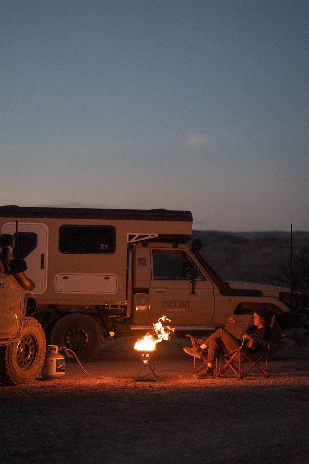 FireFold propane fire pit set near an overlanding camper at dusk